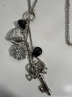 Close-up of pendant cluster showing key, heart, rhinestone medallion and black teardrop beads