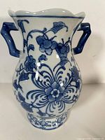 Front view of porcelain vase showing handles, floral decoration, pedestal base