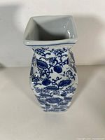 Top and side view showing square mouth, tapered body, blue floral decoration
