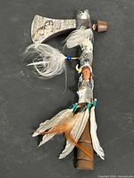 Full view of decorative tomahawk showing head, handle and feather adornments