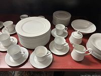 Overall view of stacked dinner plates, teacup/saucer sets, soup bowls, dessert plates, sugar bowl, and creamer