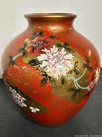 Full view of red and gold ceramic vase showing hand-painted floral decoration
