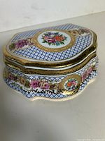 Overall view of porcelain trinket box showing floral lid design, blue lattice pattern and gold trim