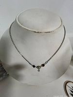 Full view of necklace on display form showing chain, rhinestone flower pendant, and blue beads