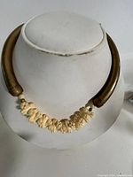 Full necklace on bust showing metal tubes and carved flowers