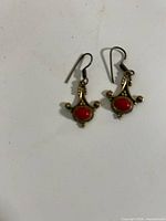 Front view of both earrings showing brass filigree and red cabochons