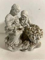 Front view of bisque porcelain figural group with two seated figures and flower basket