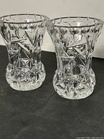 Two identical small cut crystal bud vases on dark surface