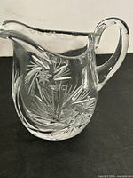 front view of clear cut crystal creamer showing pinwheel pattern and handle
