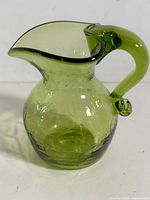 Front view of green crackle glass pitcher showing body, spout, handle attachment