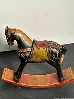 Left side view of the carved wooden rocking horse showing overall form and painted details