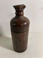 Full view of brown stoneware bottle front showing ribbed shoulders and body