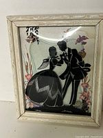Full view of framed reverse-painted silhouette art piece