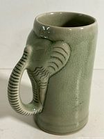 Mug side view showing elephant head and trunk handle, crackle glaze