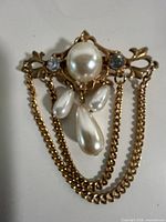 Front view showing central faux pearl, rhinestones, teardrop dangles and chain swags