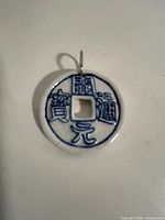 front view of ceramic coin pendant showing characters, square aperture and bail