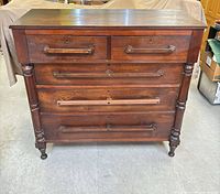 Front view showing five drawers, turned columns, wood pulls