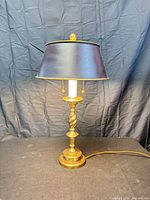 Full view of lamp showing brass base, white column, twisted stem, black shade
