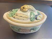Side view of casserole with lid showing rabbit knob and painted vegetables