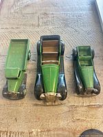 Front view of three vintage diecast vehicles: flatbed truck, streamlined car, small roadster