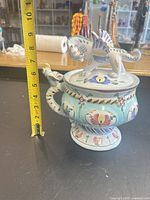 Full view of covered jar beside tape measure showing height