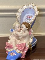 Front angled view of porcelain shoe figurine with two cherubs