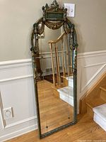 Full view of tall neoclassical mirror leaning against wall