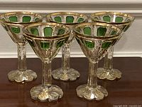 Front view of five goblets showing emerald panels and gilding