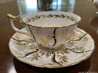 Teacup on saucer showing front design, cobalt and gold leaf
