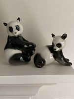 Front view of seated mother and reclining baby panda figurines