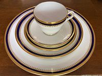 Stacked place setting showing cobalt band and gold rim