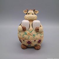 Front view of beige ceramic cow holder with two white shakers