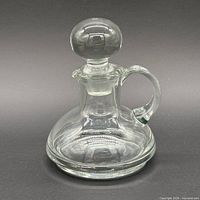 Front view of clear glass decanter with stopper showing handle and base