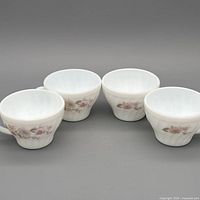 Set of four matching milk glass teacups showing uniform pattern and condition
