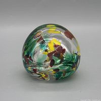 Front view of spherical glass paperweight showing color inclusions