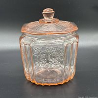 Front view of pink Depression glass cookie jar with lid showing Royal Lace pattern and ribbed panels