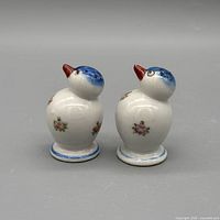 Side view highlighting blue head, red beak, floral design, pedestal base