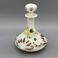 Front view of milk glass decanter showing floral painting and stopper