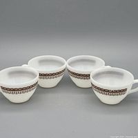 All four matching milk glass cups arranged together showing pattern and handles