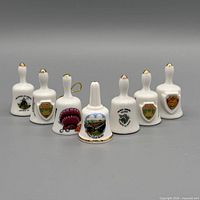 Group view of all seven white porcelain souvenir bells, front perspective