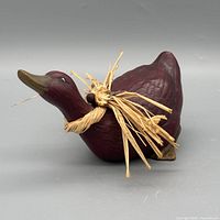 left side view of burgundy ceramic duck with raffia bow