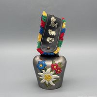 Front view of cowbell showing floral painting and strap with fringe