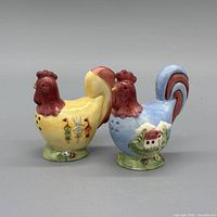 Front view of both rooster shakers showing colors and painted motifs