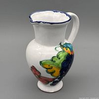 Full view left side showing grape motif and blue-edged spout