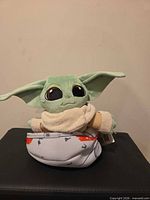 Front view of Grogu plush seated in fabric hover pram