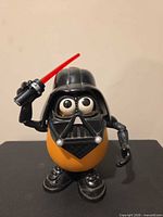 Front view of Darth Vader Mr. Potato Head holding red lightsaber