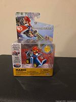 Front of sealed package showing Mario Kart die-cast pull-back vehicle and coin