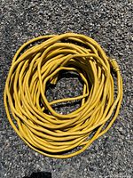 Coiled yellow heavy-duty extension cord laid on asphalt