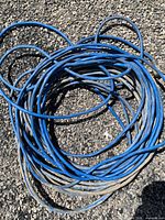 Coiled blue heavy duty extension cord on gravel surface