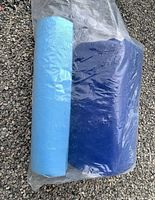 Two rolled sleeping pads in plastic bag, one light blue foam, one dark blue padded